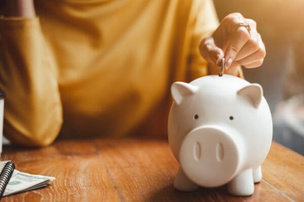 A woman depositing a coin into a piggy bank.
